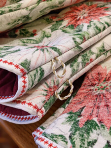 close up of oven mitt cuffs with white fabric border and red star-like stitching