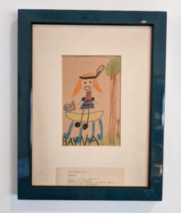 Framed photo of childhood artwork of a girl with ponytails riding a horse
