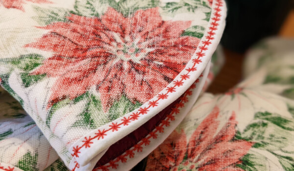 close up of christmas oven mitt red poinsettia on white background with a white fabric cuff and red star-like trim