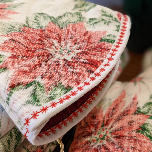 close up of christmas oven mitt red poinsettia on white background with a white fabric cuff and red star-like trim