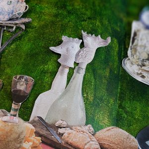 Close up of collage elements, white bottles in the shape of animals on a dark green background